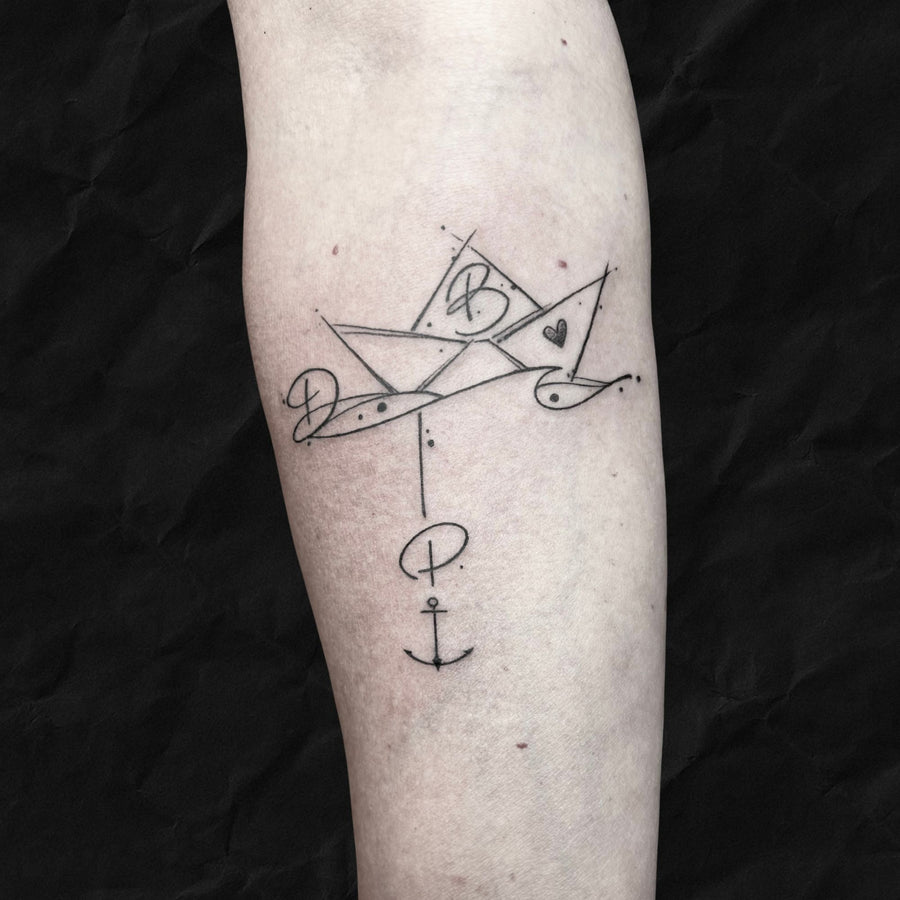 Fineline Sketch Tattoo papierschiff mit 3 Buchstaben und einem Anker von Ana aus dem Atelier Hannibal Tattoo Studio in HÜrth