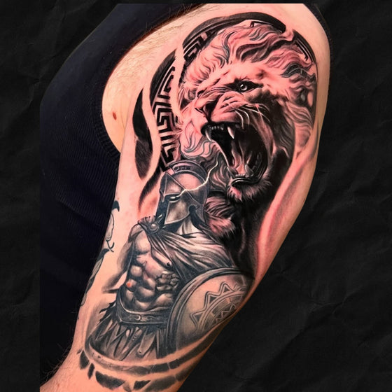 realistisches Löwen Tattoo mit spartaner, black and grey vom Atelier Hannibal Tattoo Studio in Hürth