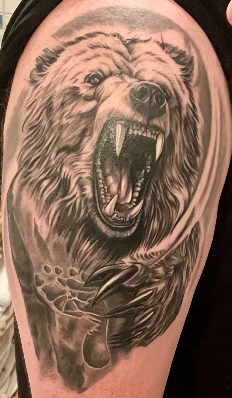 Realistisches Bären-Tattoo mit original Fußabdruck vom Sohn in Black & Grey auf Oberarm – Tattoo-Kunst von Atelier Hannibal Hürth