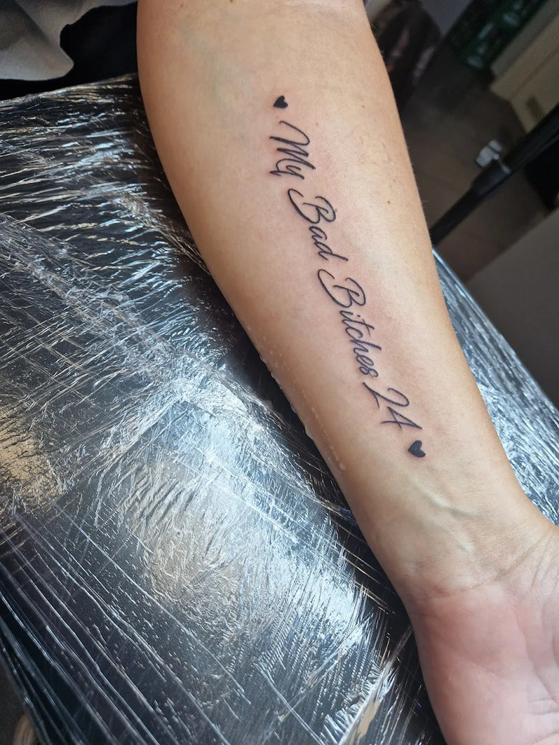 Frisches Schriftzug-Tattoo "My bad bitches 24"auf Unterarm in schwarzer Tinte; Lettering Tattoo von Atelier Hannibal Hürth