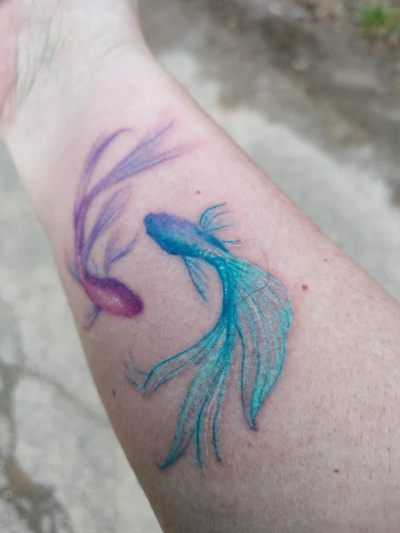 Farbiges Fisch-Tattoo in Türkis und Lila auf Unterarm – WaterColor Tattoo von Atelier Hannibal Hürth