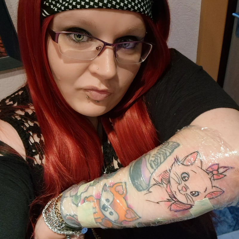 Zufriedene Kundin mit frischem Anime-Tattoo von Atelier Hannibal Hürth